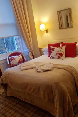 a bedroom with a bed with red pillows and a window at Sonas Guesthouse in Edinburgh