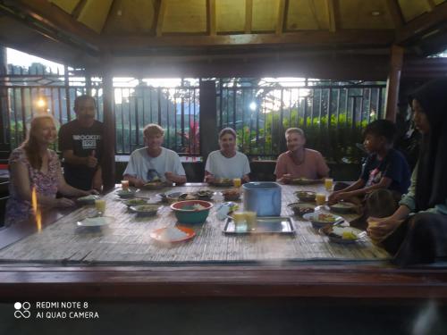 a group of people sitting around a table eating food at Akria Bed and breakfast in Bayan