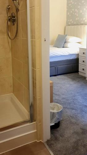 a bathroom with a shower and a bed in a room at Sonas Guesthouse in Edinburgh