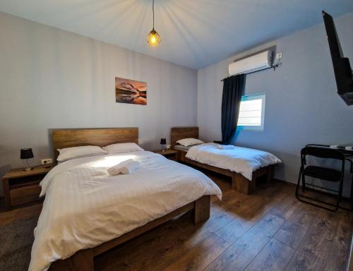 a bedroom with two beds and a television in it at XXL Rooms Osijek in Osijek