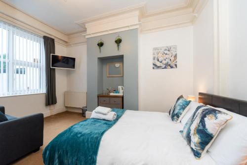 Un dormitorio con una gran cama blanca con sábanas azules. en The Weatherdene, en Great Yarmouth
