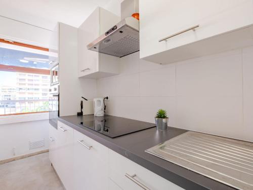 une cuisine avec des armoires blanches et un comptoir noir dans l'établissement Apartment Le Méditerranée-1 by Interhome, à Fréjus