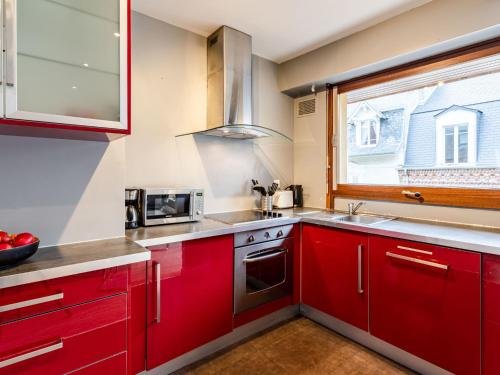 ドーヴィルにあるApartment Les Cigognes by Interhomeの赤いキャビネットと窓付きのキッチン
