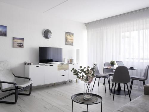 a white living room with a tv and a table at Apartment Lago di Lugano-5 by Interhome in Bissone