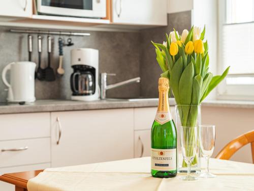 a bottle of champagne sitting on a table with a vase of flowers at Apartment Stolzenfels-1 by Interhome in Ostseebad Sellin