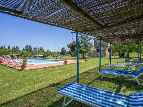 a group of blue benches under awning next to a pool at Apartment Fattoria Petraglia - Cedro by Interhome in Monteriggioni