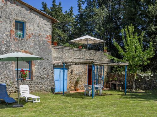 a stone house with a table and chairs and an umbrella at Apartment Fattoria Petraglia - Cedro by Interhome in Monteriggioni
