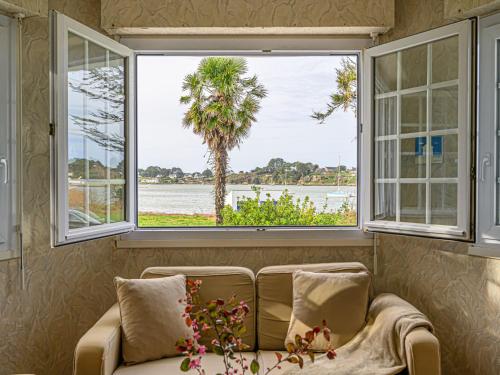 a couch in a room with two windows and a palm tree at Apartment Le Moulin by Interhome in Saint-Philibert
