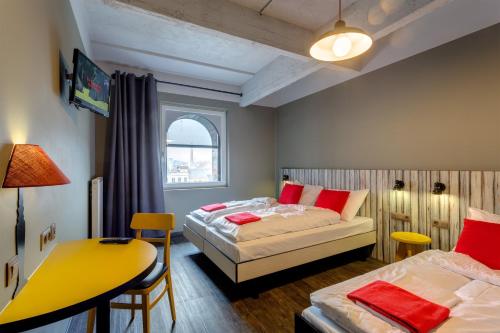 a bedroom with two beds and a table and a desk at MEININGER Hotels Bruxelles City Center in Brussels