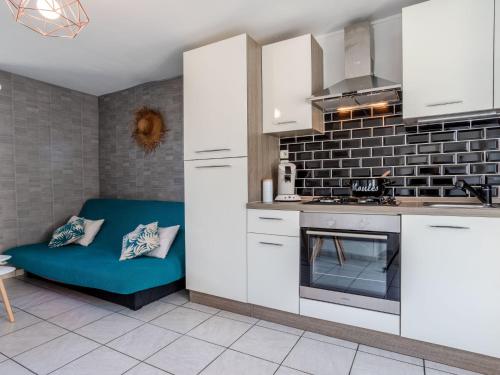 une cuisine avec des placards blancs et un canapé bleu dans l'établissement Holiday Home L'oyat by Interhome, à Pirou