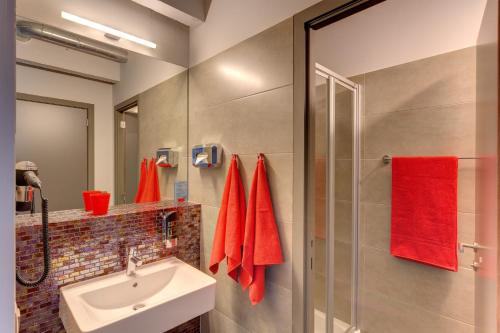 a bathroom with a sink and a shower with red towels at MEININGER Hotels Bruxelles City Center in Brussels
