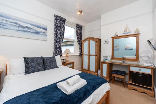 a bedroom with a bed and a desk and a mirror at The Weatherdene in Great Yarmouth