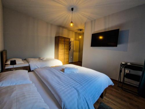 a hotel room with two beds and a flat screen tv at XXL Rooms Osijek in Osijek