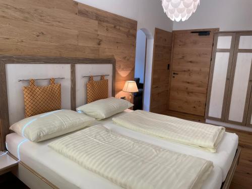 two beds in a bedroom with wooden walls at Bierhotel Loncium & Privatbrauerei in Kötschach