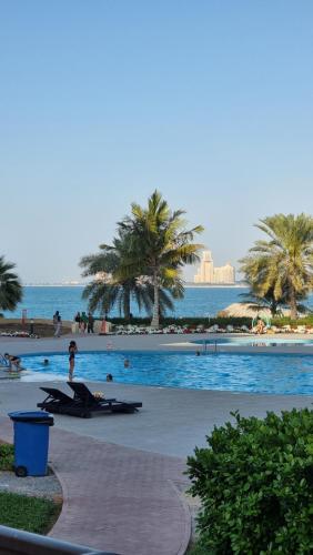 a swimming pool with palm trees and the ocean at Nice big Studio Casino view first line in Ras al Khaimah