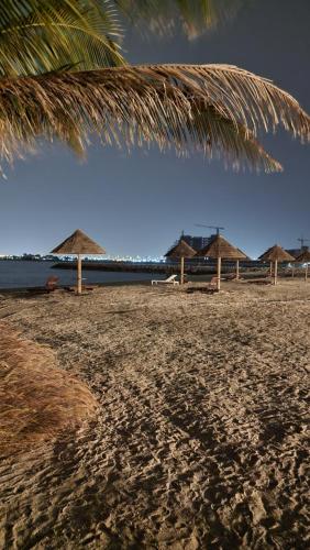 a beach with some straw umbrellas and the ocean at Nice big Studio Casino view first line in Ras al Khaimah