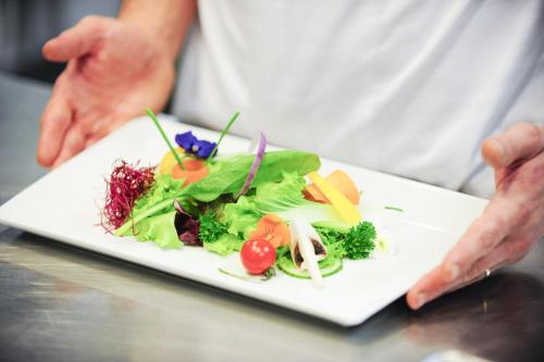 a person holding a plate of food on a table at Le Bristol Leukerbad in Leukerbad
