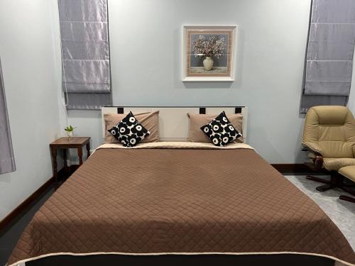 een slaapkamer met een groot bed en een stoel bij New Home บ้านเดี่ยว สร้างใหม่ ใกล้ทะเล ใจกลางเมืองระยอง in Rayong