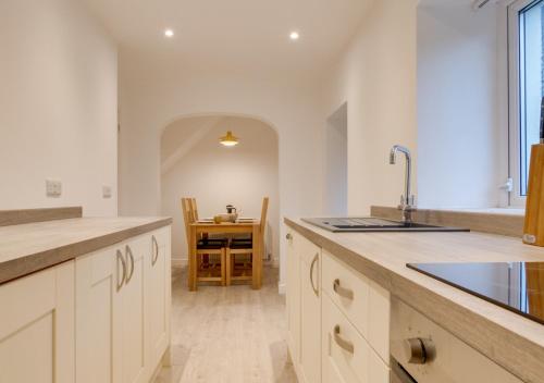 a kitchen with white cabinets and a sink and a table at Uwch Ogwen in Bethesda