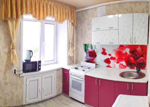 una cucina con armadi rossi e bianchi e un lavandino di 4-х комнатная квартира Центр ЦУМ a Qostanay