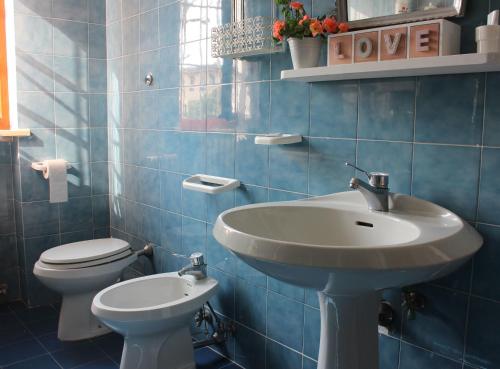 a blue tiled bathroom with a sink and a toilet at "Lilla" in Calci