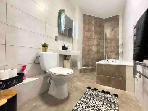 a bathroom with a toilet and a tub and a sink at Central Luton apartment by Hostaguest in Luton