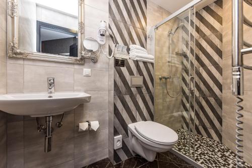 a bathroom with a toilet and a sink and a shower at Resort Hotel Elija in Šventoji