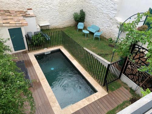a swimming pool in a yard with two chairs and a fence at Agréable maison de ville clim/piscine/jardin in Nîmes