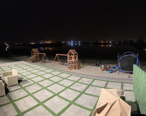 a dock with chairs and a playground at night at منتجع اووه يامال البحري في الخيران OOh Yaa Mal in Al Khīrān