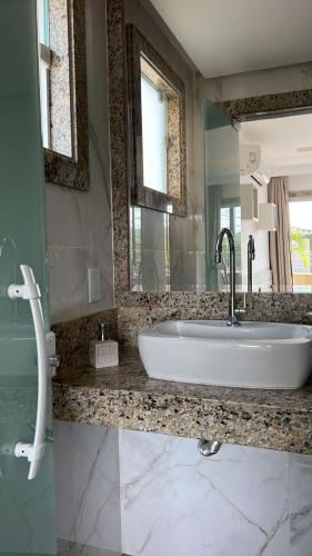 a bathroom with a sink and a large mirror at Pérola de Geribá in Búzios