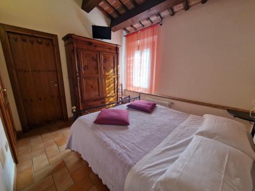 ein Schlafzimmer mit einem Bett mit lila Kissen darauf in der Unterkunft Agriturismo e Cantina La Sabbiona in Faenza