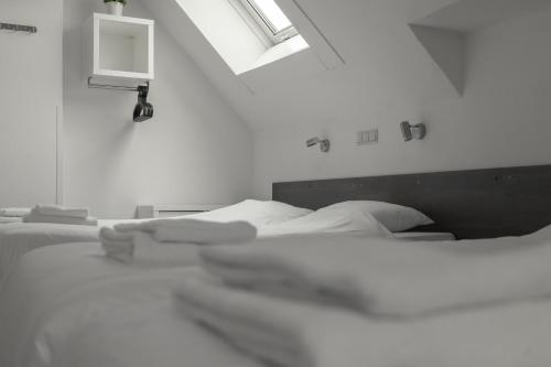 a group of white beds in a room with a window at Hotel de la Bourse in Maastricht