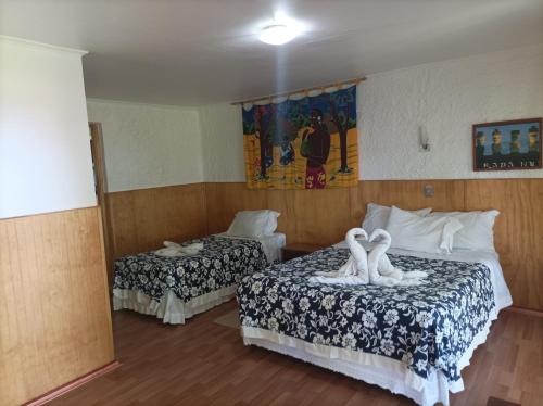 a hotel room with two beds with swans on them at Cabañas MANA NUI INN in Hanga Roa