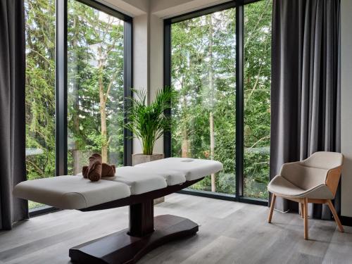 シュクラルスカ・ポレンバにあるHotel Bergo Resort & SPAの白いベンチと大きな窓が備わる客室です。