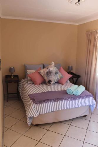 Swartbessie Geusthouse في كروغرسدورب: غرفة نوم عليها سرير ومخدات