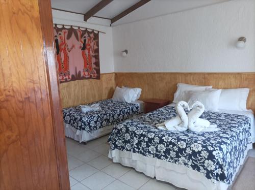 two swans are sitting on two beds in a hotel room at Cabañas MANA NUI INN in Hanga Roa