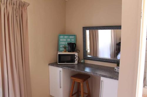 a kitchen with a counter with a microwave and a mirror at Swartbessie Geusthouse in Krugersdorp