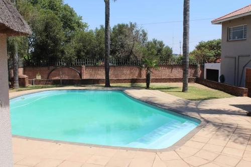 a large blue swimming pool in a yard at Swartbessie Geusthouse in Krugersdorp
