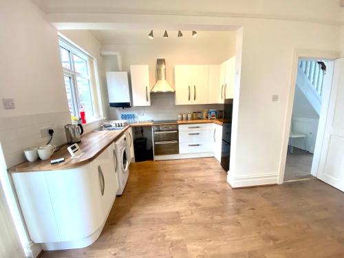 a kitchen with white cabinets and a wooden floor at Merseyside in Birkenhead