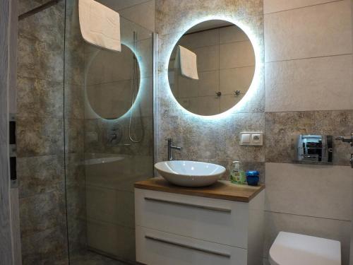 a bathroom with a sink and a shower with two mirrors at Apartament Plac Piastowski 1 in Jelenia Góra