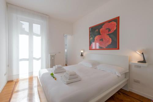 a white bedroom with a large white bed with towels on it at BnButler - Verona 12, Porta Romana District in Milan