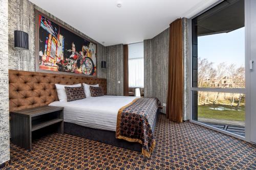 a hotel room with a bed and a large window at Resort Hotel Elija in Šventoji