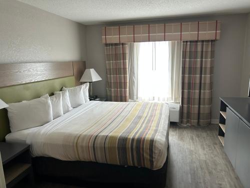 a hotel room with a bed and a window at Country Inn & Suites by Radisson, Grand Rapids Airport, MI in Grand Rapids