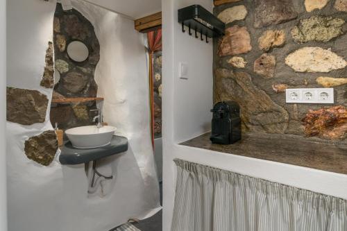 La salle de bains est pourvue d'un lavabo et d'un mur en pierre. dans l'établissement Akrogialis Sirma Klima, à Adamas