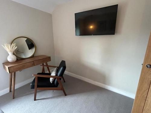a room with a mirror and a chair and a television at Caernarfon modern townhouse Snowdonia in Caernarfon