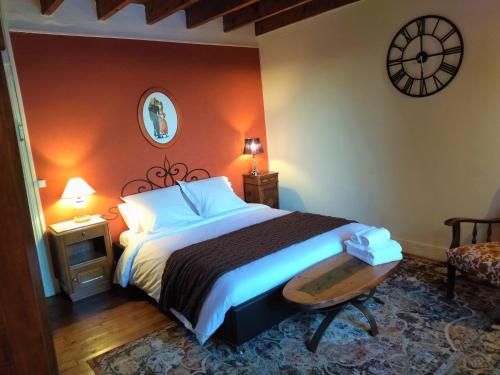 a bedroom with a bed and a clock on the wall at La Halte du Pèlerin Chambres d'hôtes in Chérier