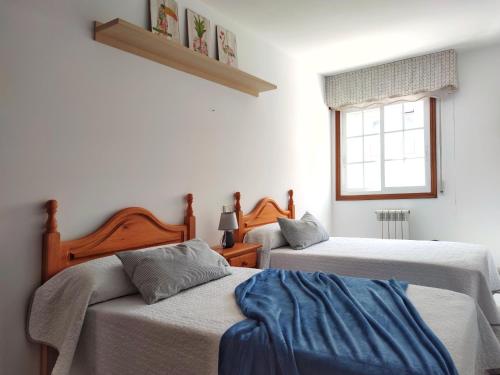 1 dormitorio con 2 camas y ventana en Desconectaengalicia Cesteiros, piscina, 100m Playa Silgar, en Sanxenxo