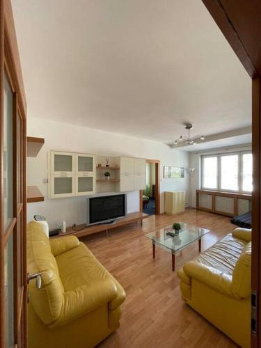 sala de estar con sofá amarillo y mesa en Apartmán Obchodná, en Staré Mesto