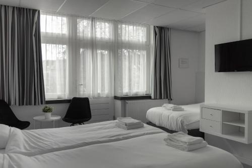 a hotel room with two beds and a television at Hotel de la Bourse in Maastricht