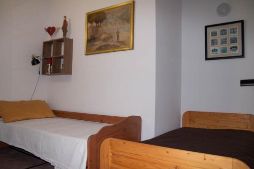 a bedroom with two beds and a picture on the wall at Három Tarka Macska Apartmanok in Sárospatak